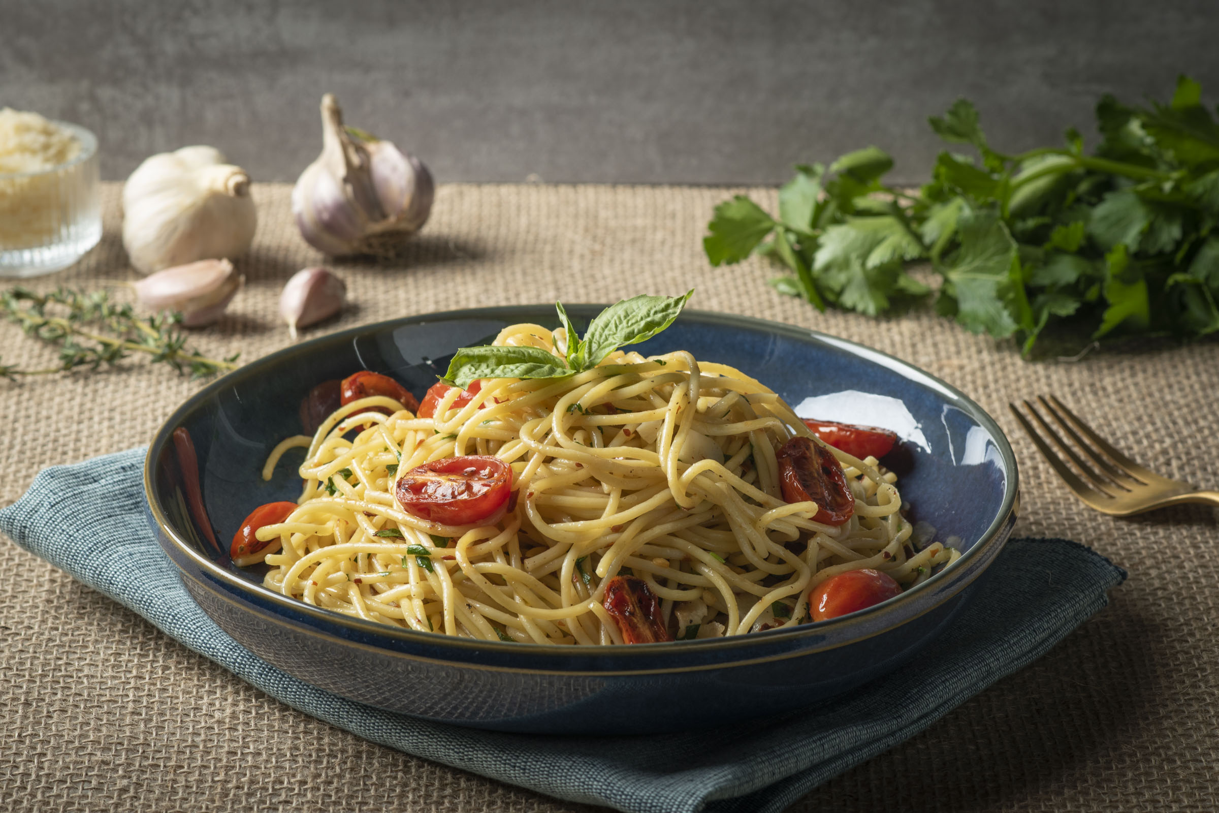 A bowl of aglio e olio pasta served with tomatoes
